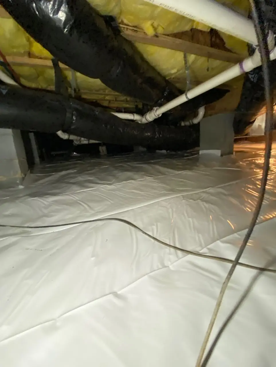 Encapsulated crawlspace with white ground vapor barrier and insulated ductwork overhead