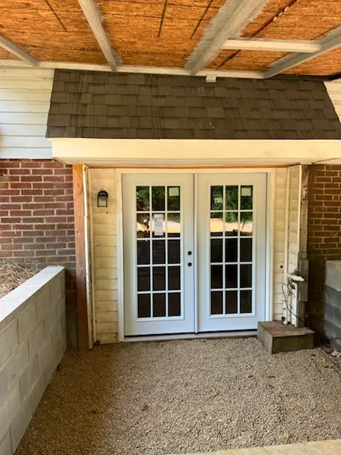 New white French doors installed at the rear entrance of the backyard hangout area