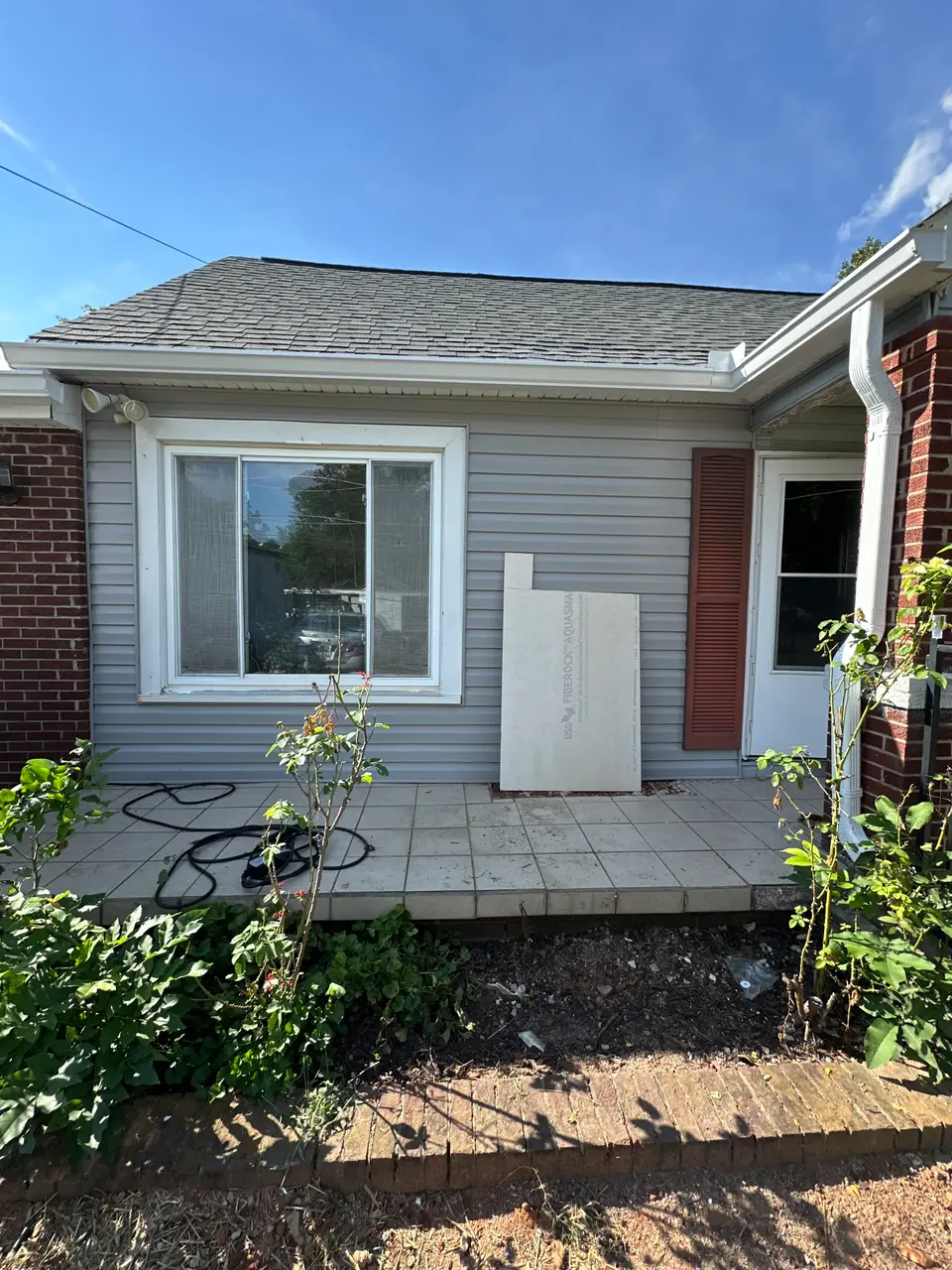 Rear wall of the home with cement backer board staged near the window during exterior work