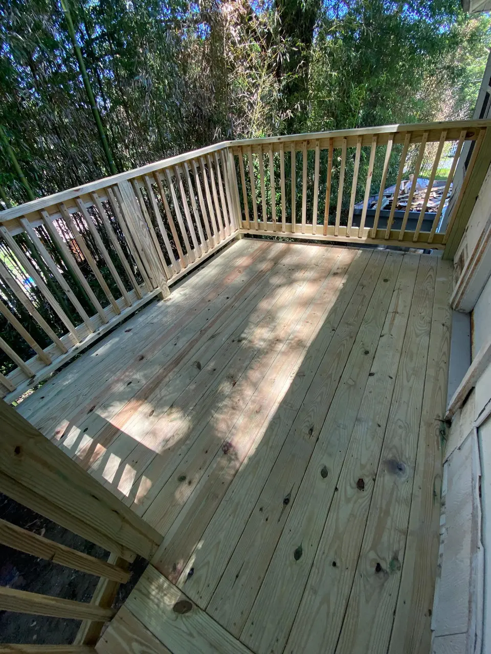 Finished wood deck with new railing overlooking a wooded backyard