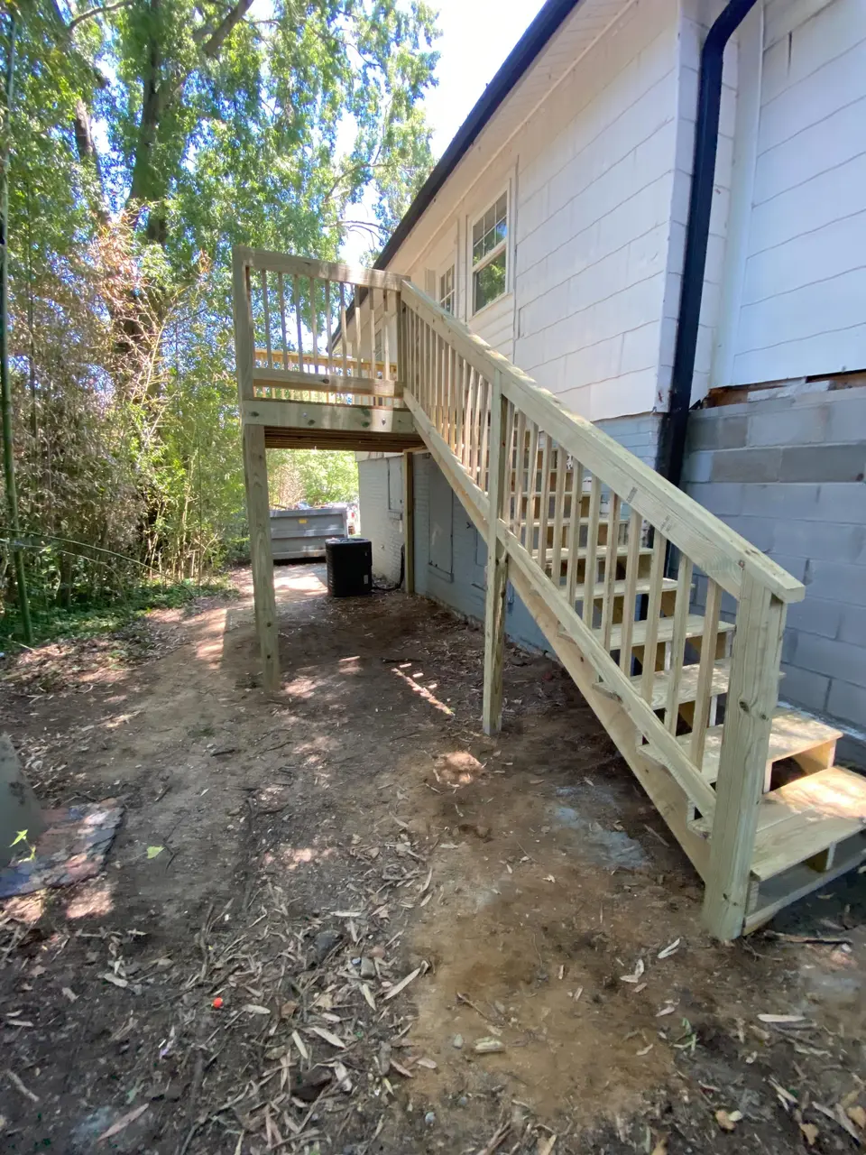 Finished elevated wood deck and staircase attached to the side of a house