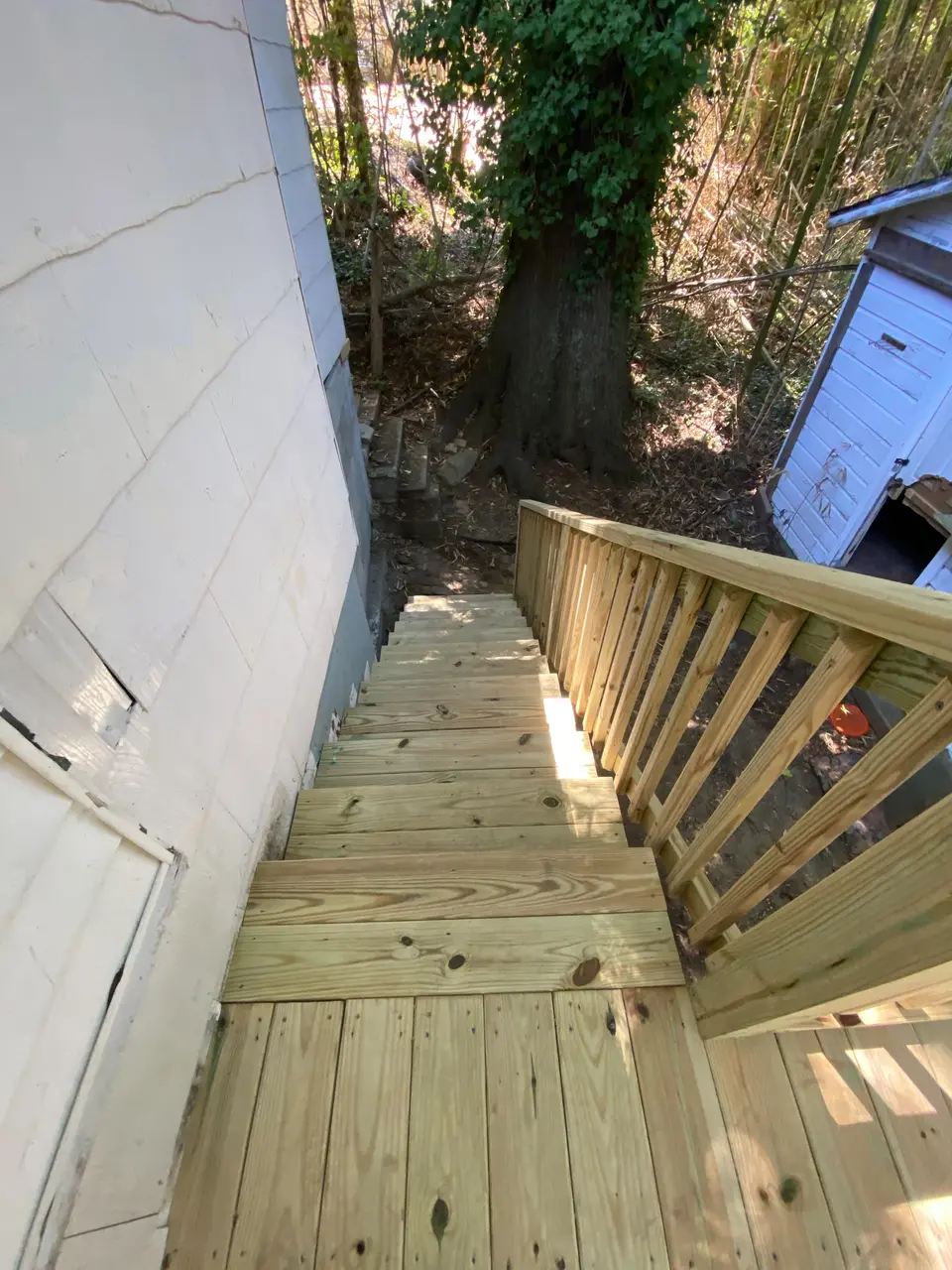 New wood deck staircase with railing leading down into a wooded yard