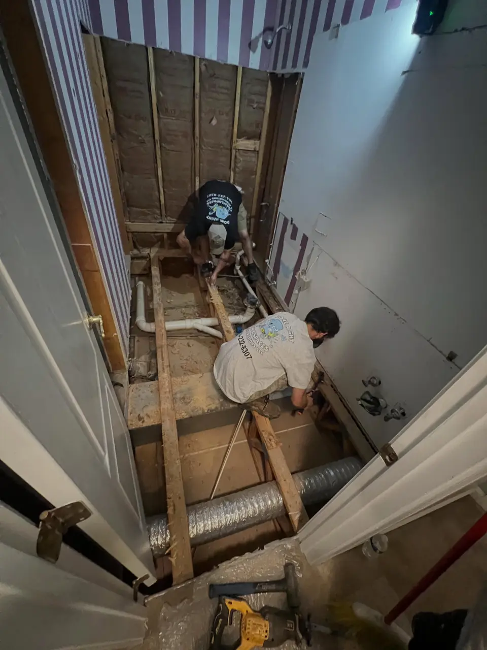 Bathroom remodel in progress with subfloor and plumbing rough-in exposed