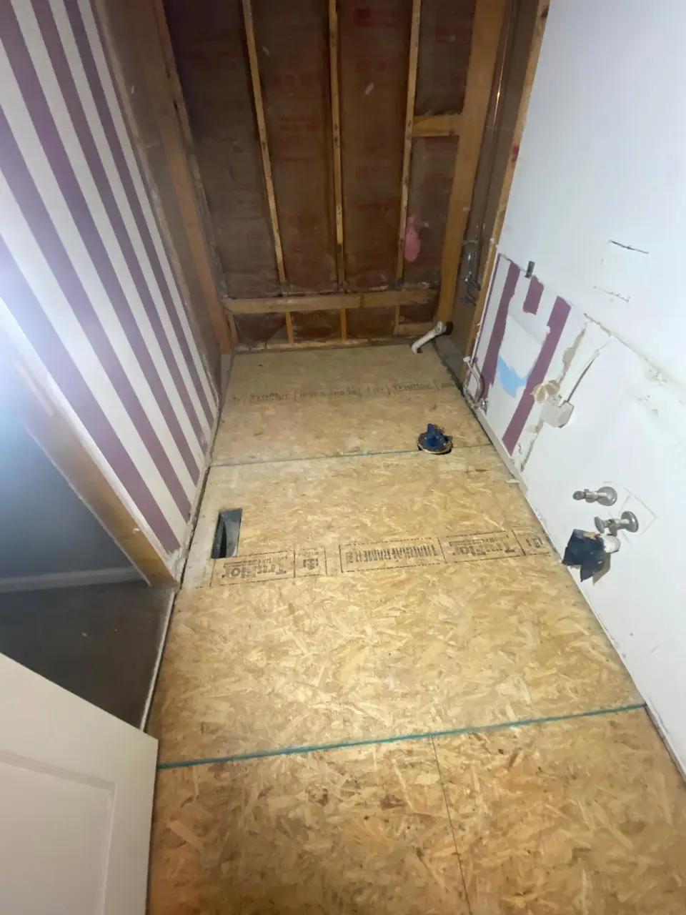 Bathroom remodel with new subfloor installed and wall framing exposed